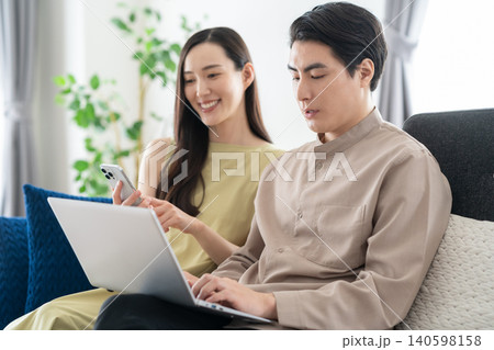 リビングでパソコンとスマホを見るミドルの夫婦 140598158