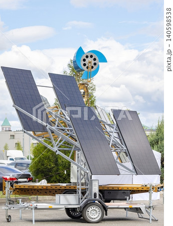 Solar panels on a trailer with wind turbine setup in an outdoor scene during the day Solar panels on a trailer with wind turbine setup in an outdoor scene during the day 140598538