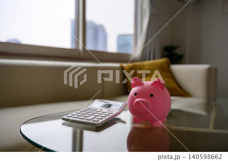ピンクの貯金箱と電卓、節約の象徴 ピンクの貯金箱と電卓、節約の象徴 140598662