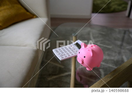 ガラスのテーブル上の貯金箱と電卓 140598688