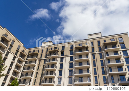 Modern apartment building facade with balconies against a blue sky Modern apartment building facade with balconies against a blue sky 140600105