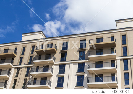 Modern apartment building facade with balconies against a blue sky 140600106