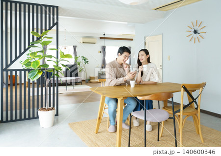 自宅のテーブルでスマホを見ながら飲み物を飲む若い日本人パワーカップ持つ若い日本人女性のパワーカップル 140600346
