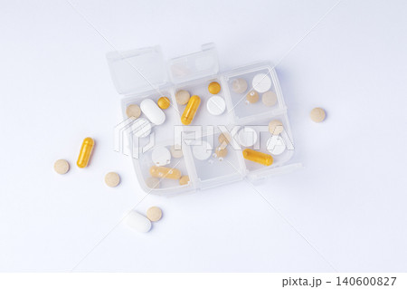 Pill box organizer with capsules and tablets on white background, daily medication and supplement Pill box organizer with capsules and tablets on white background, daily medication and supplement 140600827