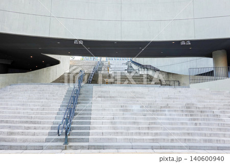 Modern concrete building architecture with wide stone stairs and metal railings 140600940