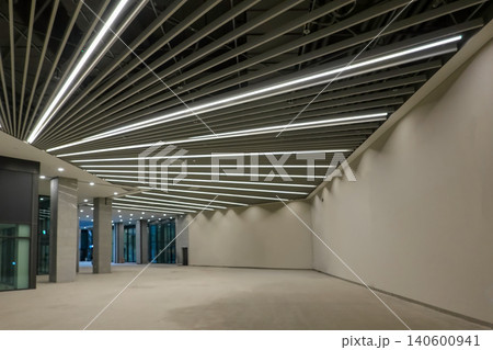 Modern building interior with abstract linear ceiling lighting and empty hall Modern building interior with abstract linear ceiling lighting and empty hall 140600941