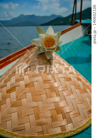 White water lily on straw hat on boat at lake with mountains scenic nature photo 140602186