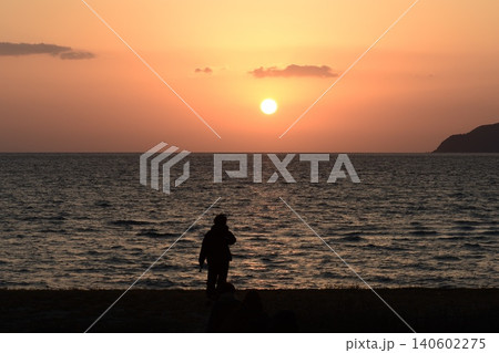 冬の海岸の水平線に沈みかけた夕日 冬の海岸の水平線に沈みかけた夕日 140602275