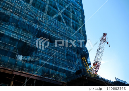 ブルーの養生ネットに覆われた巨大な建設現場と大型クレーン 140602368