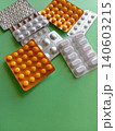 A bunch of pills are scattered on a green surface The pills are of different colors and shapes, and they appear to be in various stages of being opened. Concept of disarray and confusion 140603215