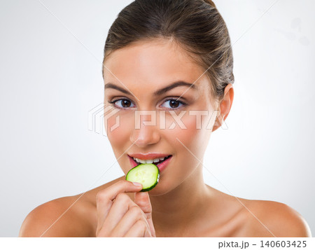 Woman, portrait or cucumber for eating in studio with wellness detox, healthy vegetable or nutrition diet. Model, person or fruit for organic cosmetics, natural beauty or skincare on white background 140603425