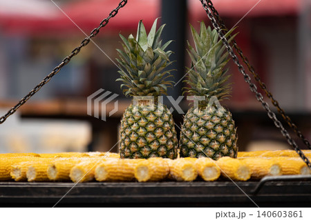 Two pineapples on outdoor grill corn cobs eye level view Two pineapples on outdoor grill corn cobs eye level view 140603861