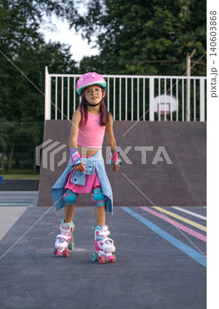 A girl on roller skates squares riding in a skate park. Full protective sports equipment for child safety A girl on roller skates squares riding in a skate park. Full protective sports equipment for child safety 140603868
