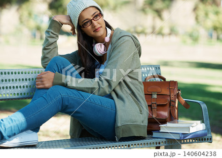 Thinking, relax and student in park with books for studying, learning and reading outdoors. Education, happy and person with bag, textbooks and headphones on bench for university, campus or college 140604238