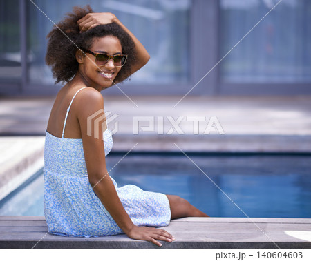 African woman, outside and pool for vacation in summer, sitting and happy for trip with sunglasses. Holiday for relax and casual for swimming and happiness for wellness with natural female model African woman, outside and pool for vacation in summer, sitting and happy for trip with sunglasses. Holiday for relax and casual for swimming and happiness for wellness with natural female model 140604603