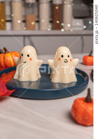 Cute ghost-shaped marshmallow desserts on blue plate with mini pumpkins Cute ghost-shaped marshmallow desserts on blue plate with mini pumpkins 140605040