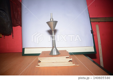 Metal funnel standing on top of stacked thin wooden boards with construction Metal funnel standing on top of stacked thin wooden boards with construction 140605580