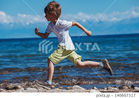 Boy running on the lake shore at sunny day Boy running on the lake shore at sunny day 140607317