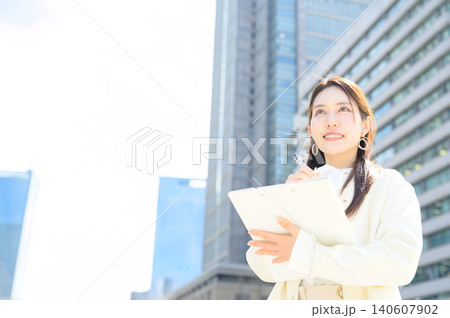 オフィス街でクリップボードに記入する日本人ビジネスウーマン オフィス街でクリップボードに記入する日本人ビジネスウーマン 140607902