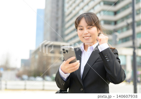 スマートフォンを見て喜ぶ20代日本人女性会社員 スマートフォンを見て喜ぶ20代日本人女性会社員 140607938