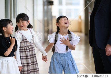 学校の廊下に並んで笑顔で立つ男性教師と女子小学生たち 学校の廊下に並んで笑顔で立つ男性教師と女子小学生たち 140608654