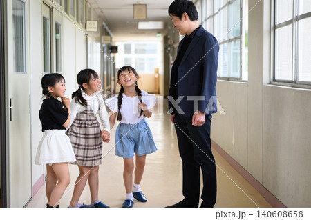 学校の廊下に並んで笑顔で立つ男性教師と女子小学生たち 学校の廊下に並んで笑顔で立つ男性教師と女子小学生たち 140608658