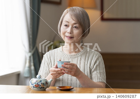 ダイニングでお茶を入れるシニア女性 140609287