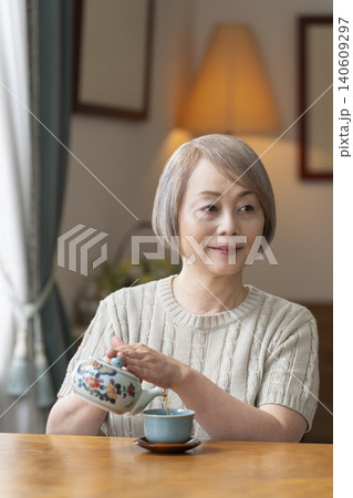 ダイニングでお茶を入れるシニア女性 ダイニングでお茶を入れるシニア女性 140609297