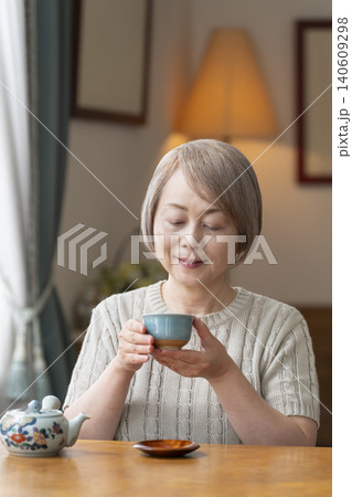 ダイニングでお茶を入れるシニア女性 140609298
