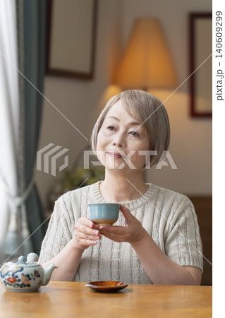 ダイニングでお茶を入れるシニア女性 ダイニングでお茶を入れるシニア女性 140609299