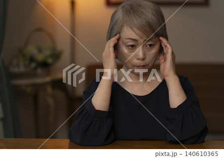 リビングで体調不良で頭をかかえるシニア女性 140610365