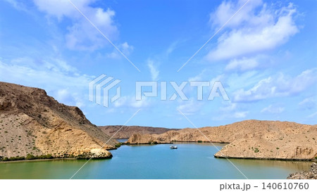 Tourism destination, turquoise inlet surrounded by arid rocky hills under blue sky Tourism destination, turquoise inlet surrounded by arid rocky hills under blue sky 140610760
