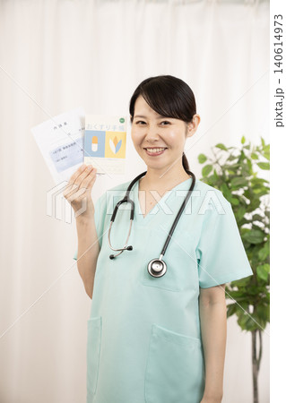 お薬手帳と薬袋を持つ看護師さん お薬手帳と薬袋を持つ看護師さん 140614973