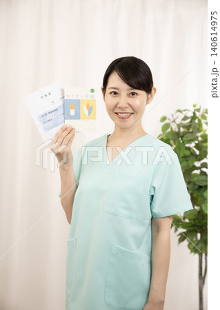 お薬手帳と薬袋を持つ看護師さん お薬手帳と薬袋を持つ看護師さん 140614975