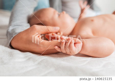 A baby is holding on to the mother's finger. Side view. Concept of motherhood and children's day 140615135