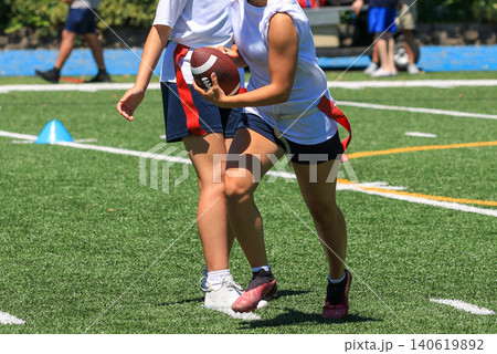 Girls Play Flag Football with Quarterback Handing Off the Football to a Running back Girls Play Flag Football with Quarterback Handing Off the Football to a Running back 140619892