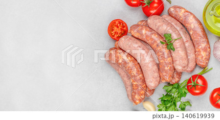 Raw sausages with tomatoes parsley and olive oil on gray background with copy space Raw sausages with tomatoes parsley and olive oil on gray background with copy space 140619939