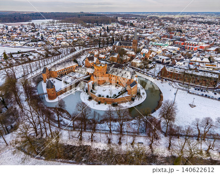 Aerial view of the historic Huis Bergh castle covered in snow with a water moat and traditional town architecture in Heerenberg, Gelderland, Netherlands during winter. 140622612