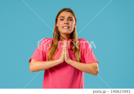 Believer Young Woman Praying With Crossed Fingers, Blue Background. Hope Believer Young Woman Praying With Crossed Fingers, Blue Background. Hope 140623991