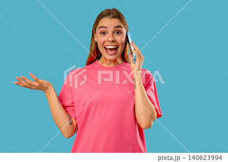 Amazed blonde woman talking by phone, nice joke, smiling. Young lady on Blue 140623994
