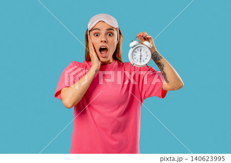Woken Up By Alarm Clock Shocked Young Woman On blue Background, Laziness Woken Up By Alarm Clock Shocked Young Woman On blue Background, Laziness 140623995