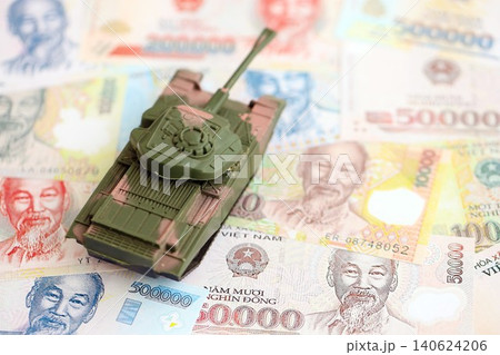 Vietnamese dong currency money bills and toy tank. The concept of army funds and weapons sales Vietnamese dong currency money bills and toy tank. The concept of army funds and weapons sales 140624206