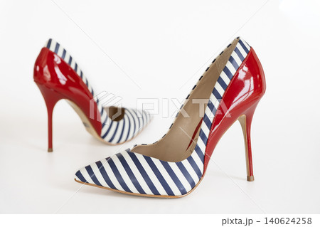 Pair of striped navy high heel shoes with red accents on white studio background Pair of striped navy high heel shoes with red accents on white studio background 140624258