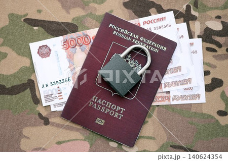 Russian rubles money bills and passport under ban of heavy lockpad close up. Concept of sanctions Russian rubles money bills and passport under ban of heavy lockpad close up. Concept of sanctions 140624354