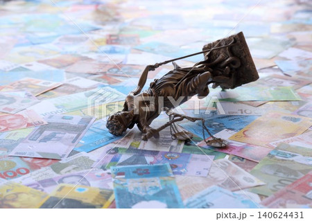Themis figure against the background of pile of different currency money bills. Concept of justice Themis figure against the background of pile of different currency money bills. Concept of justice 140624431