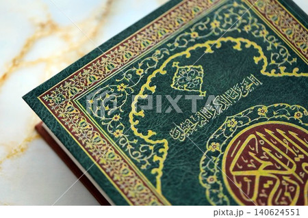 Al Quran Muslim holy book on table in mosque. Details of arabic calligraphy on islamic book cover Al Quran Muslim holy book on table in mosque. Details of arabic calligraphy on islamic book cover 140624551