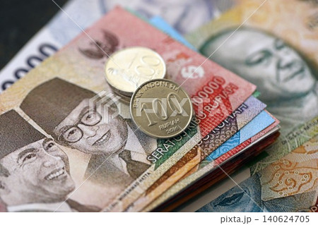Indonesian rupiah money bills and sen coins pile. Indonesia coins on banknotes of IDR currency Indonesian rupiah money bills and sen coins pile. Indonesia coins on banknotes of IDR currency 140624705