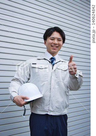 作業服を着てヘルメットを持つ笑顔の若い男性 作業服を着てヘルメットを持つ笑顔の若い男性 140624842