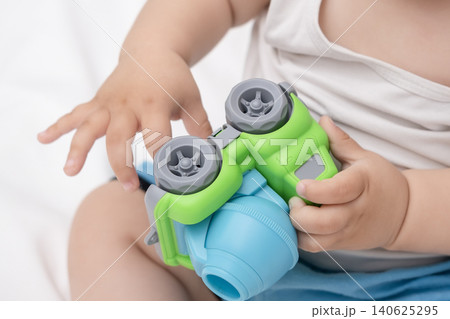 Close-up of baby hands holding and playing with a colorful toy concrete mixer truck 140625295