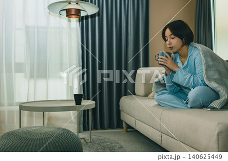 ソファでくつろぎコーヒーを飲む女性 140625449